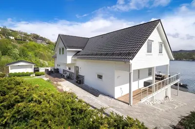 a white house with a dock on the water at Beachfront Villa with Jacuzzi, Cinema & Canoe in Bergen