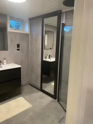 a bathroom with a shower and a sink and a mirror at Leilighet i under etasje in Lillehammer