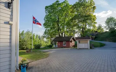 a house with a flag in front of a driveway at Cozy rooms with private bathroom close to Hønefoss in Knestang