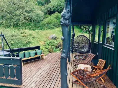 a deck with two chairs and a bird cage at Cabin by Oppstrynsvatnet, Hjelle in Stryn