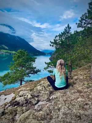 a woman sitting on a hill overlooking a lake at Cabin by Oppstrynsvatnet, Hjelle in Stryn