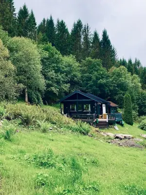 a black cabin in the middle of a grass field at Cabin by Oppstrynsvatnet, Hjelle in Stryn