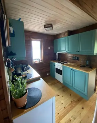 a kitchen with blue cabinets and a wooden floor at Cabin by Oppstrynsvatnet, Hjelle in Stryn
