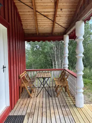 a wooden porch with two chairs and a table on it at Authentic Norwegian chalet for 8 with fireplaces & modern comfort near Geilo ski slopes in Geilo