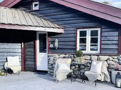 a wooden porch with chairs and a stone wall at 8 person holiday home in Hemsedal in Hemsedal