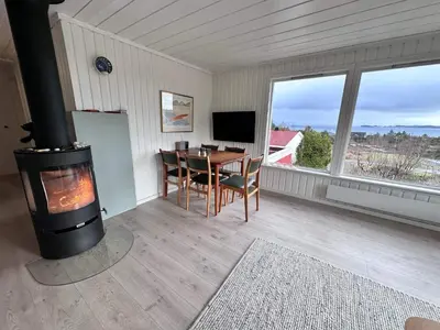 a living room with a fireplace and a table with chairs at 6 person holiday home in KLOKKARVIK in Klokkarvik