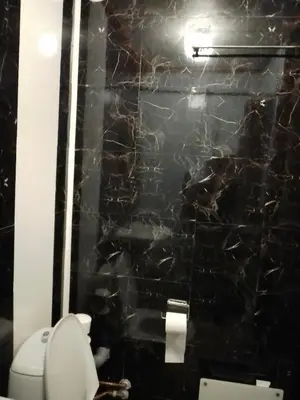 a bathroom with a black marble wall with a toilet at Cozy room away from home in Åmot