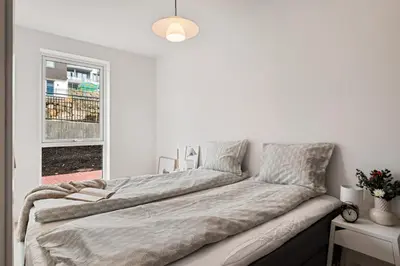a bed in a white room with a window at Helt NY leilighet, Ytre Sandviken i Bergen in Bergen
