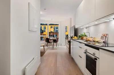 a kitchen with white cabinets and a dining room at Helt NY leilighet, Ytre Sandviken i Bergen in Bergen