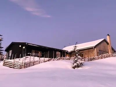 a barn covered in snow with a tree in front of it at Birkenstua in Ringsaker