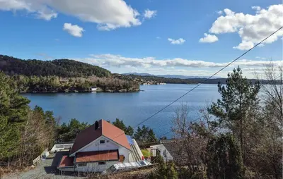 a house on a hill next to a large lake at Lovely Home In Mosterhamn With Sauna in Mosterhamn