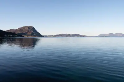 a large body of water with mountains in the background at Komfortable Ferieleiligheter med Sjøutsikt in Stadlandet