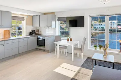 a kitchen with white cabinets and a table and chairs at Komfortable Ferieleiligheter med Sjøutsikt in Stadlandet