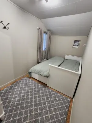 a small bedroom with a bed and a carpet at Idyllic Snekkerstuvarpet with its own pier in Lillehammer