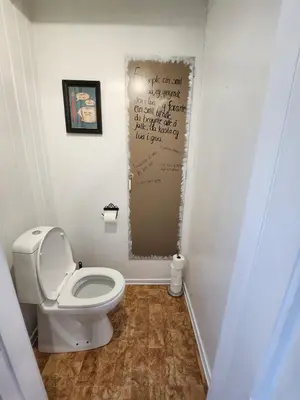 a bathroom with a toilet and a poster on the wall at Idyllic Snekkerstuvarpet with its own pier in Lillehammer