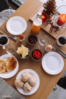 a wooden table with plates of food and orange juice at LAUV Tretopphytter in Eidsvoll