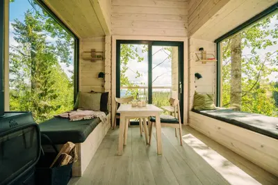 a tiny house with a window seat and a table at LAUV Tretopphytter in Eidsvoll