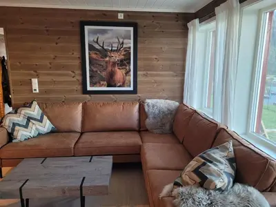 a living room with a brown couch and a picture of a deer at Apartment Tråstølen ski in ski out in Vossevangen