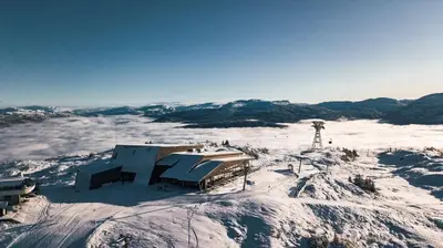 a building on top of a mountain covered in snow at Apartment Tråstølen ski in ski out in Vossevangen