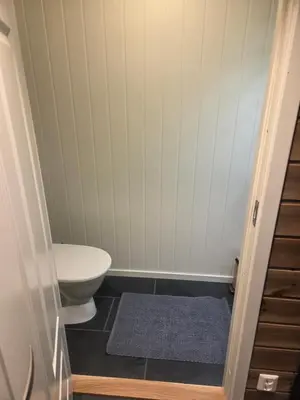 a bathroom with a toilet and a blue rug at Apartment Tråstølen ski in ski out in Vossevangen