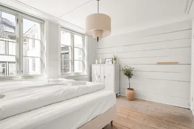 a white bedroom with a large bed and windows at Bergen Gem Straight Out of History - Built in 1750 in Bergen