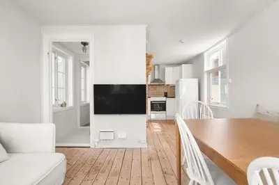a white living room with a table and a tv at Bergen Gem Straight Out of History - Built in 1750 in Bergen