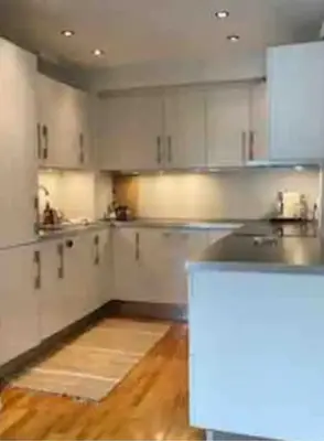 a kitchen with white cabinets and a wooden floor at Nice appartment in Bergens best location in Bergen