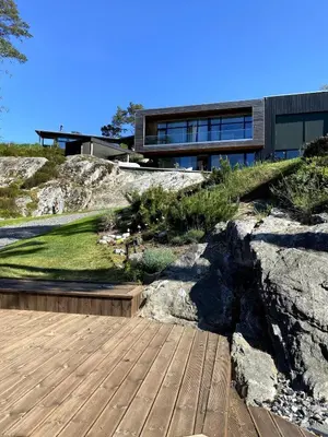 a house on top of a hill with a wooden deck at Villa Vy - a gem with private beach in Bergen in Bergen
