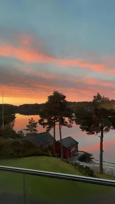 a house on the shore of a lake at sunset at Villa Vy - a gem with private beach in Bergen in Bergen