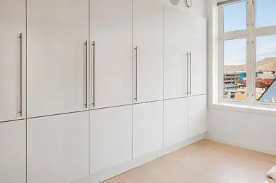 a white kitchen with white cabinets and a window at DINBNB Apartments l Luxury Penthouse l Roof Terrace l Central Bergen in Bergen