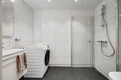 a white bathroom with a shower and a washing machine at Helt NY leilighet, Ytre Sandviken i Bergen in Bergen