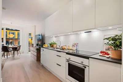 a kitchen with white cabinets and a dining room at Helt NY leilighet, Ytre Sandviken i Bergen in Bergen