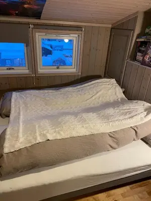 a bed in a small room with two windows at Lars sitt hus in Lillehammer