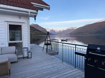a house with a deck with a view of a lake at Stryn Fjord Lodge Faleide in Stryn