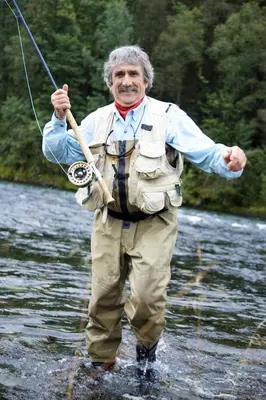 a man standing in a river holding a fishing rod at Mo Laksegard in Sand