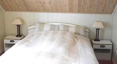 a bedroom with a white bed with two lamps at Jordbærstova Feriehus in Valldal