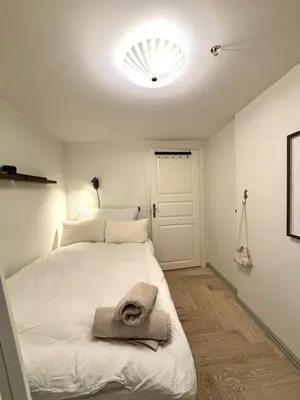 a bedroom with a white bed with a towel on it at Apartment behind Bryggen in Bergen in Bergen