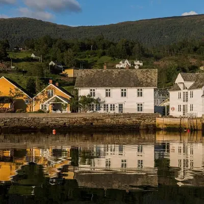 a large white house sitting next to a body of water at Kramsjø Gjestgiveri in Herand
