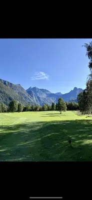 a large green field with mountains in the background at Bispen Villa Utsikten in Åndalsnes
