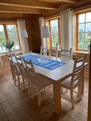 a wooden table with chairs and a dining room at Stort hus med tømmervegger og fjordutsikt in Stranda