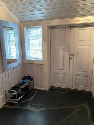 a room with a door and a shelf with shoes at Stort hus med tømmervegger og fjordutsikt in Stranda