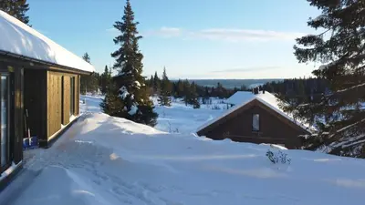a snow covered yard next to a building with a house at Modern Cabin With Mountain View By Syningtoppen in Torpo