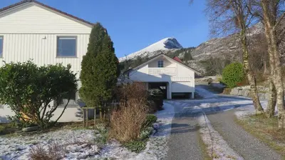 a house with a driveway and a mountain in the background at Sara's Fjord View House in Stadlandet