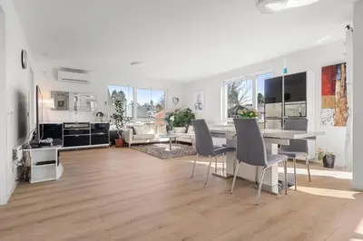 a living room with a table and chairs and a kitchen at A cozy three bedroom apartment for rent in Heimdal