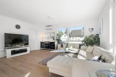 a living room with a white couch and a large tv at A cozy three bedroom apartment for rent in Heimdal