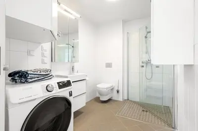 a white bathroom with a washing machine in it at A cozy three bedroom apartment for rent in Heimdal