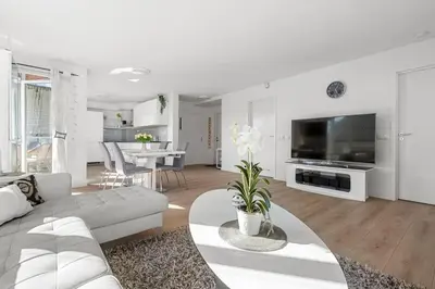 a white living room with a couch and a tv at A cozy three bedroom apartment for rent in Heimdal