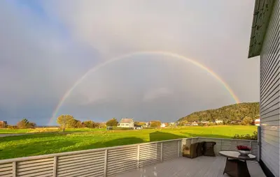 a rainbow in the sky over a yard at 3 Bedroom Cozy Apartment In Myklebost in Myklebost