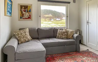 a gray couch in a living room with a window at 3 Bedroom Cozy Apartment In Myklebost in Myklebost