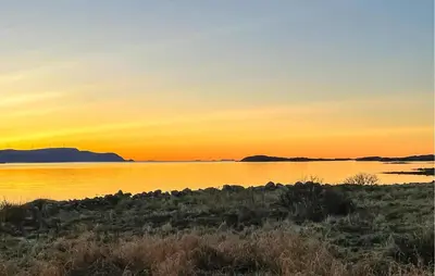 a sunset over a body of water with mountains in the background at 3 Bedroom Cozy Apartment In Myklebost in Myklebost